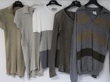 several sweaters hanging on a rack in front of a white wall
