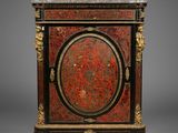 a red and black painted cabinet with gold accents