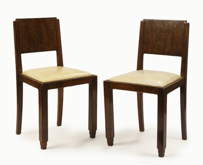 two wooden chairs with beige upholstered seats on a white background