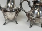 two silver teapots sitting next to each other on a table