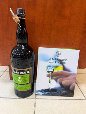 une bouteille d'alcool posée à côté d'un livre, par terre