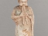 une statue représentant un homme jouant de la flûte, posée sur une table