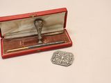un petit objet en argent dans une boîte rouge, à côté d'une pièce de monnaie