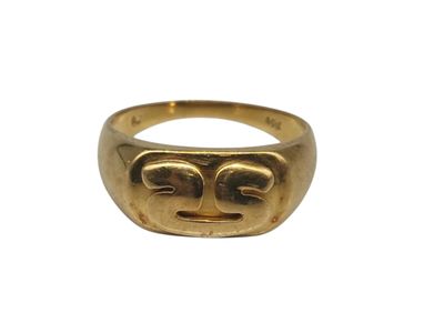 un gros plan d'une bague en or sur laquelle est gravé un visage
