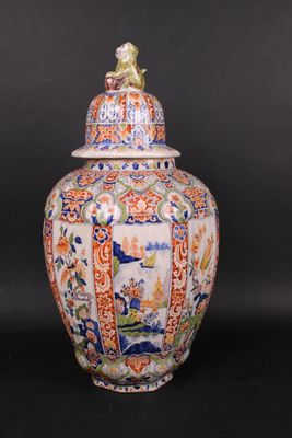 an orange and blue vase with a bird sitting on top of it