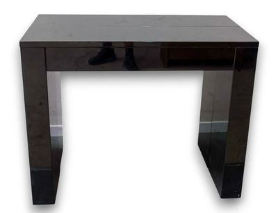 La console noire est dotée d'un plateau en verre et d'un piètement en métal.