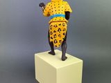 statue of a woman in a leopard print dress and hat on a white pedestal