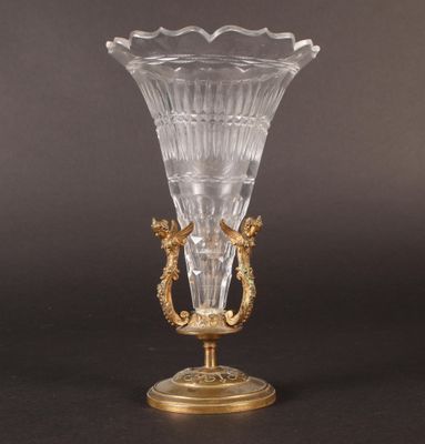 an antique glass vase on a gold stand on a black background
