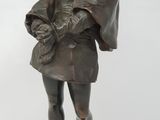statue en bronze représentant un homme coiffé d'un chapeau, posée sur un socle