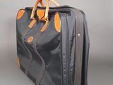 a black suitcase with orange handles on a gray surface
