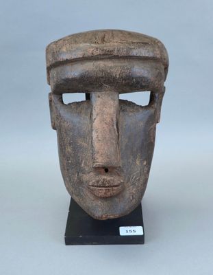 un gros plan d'un masque en bois posé sur un socle