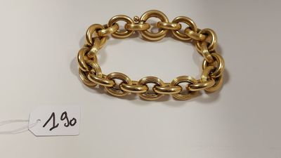 gros plan d'un bracelet en chaîne en or sur une surface blanche