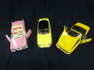 three small toy cars are lined up on a black surface
