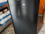 un petit réfrigérateur noir dans une pièce aux murs orange