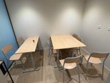 tables and chairs in a small room with a wall mounted projector screen