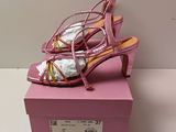 des chaussures à talons hauts roses posées sur une boîte rose, elle-même posée sur une surface blanche