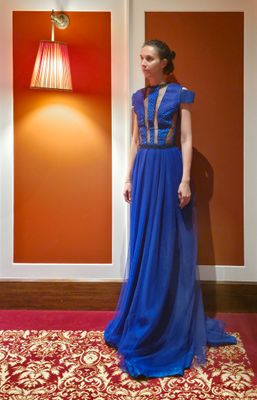 une femme en robe bleue, debout sur un tapis rouge