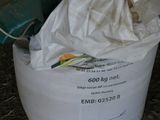 un sac de provisions posé par terre à côté d'une poubelle