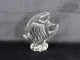 une figurine en verre représentant un poisson posée sur un fond noir