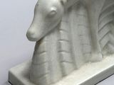 a white sculpture of a goat that is on display