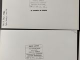 three white envelopes with black writing on them sitting on top of a table