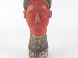 une statue rouge représentant un homme coiffé d'un chapeau