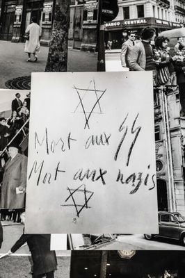 black and white photograph of a man holding a sign with writing on it