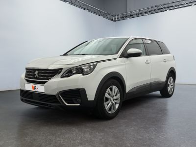 Une voiture blanche est garée dans une pièce blanche au sol noir.