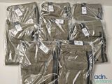 six paires de pantalons emballées dans du plastique, posées sur une table
