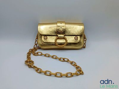 un gros plan d'un sac à main doré entouré d'une chaîne