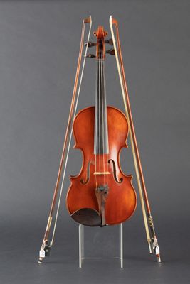 an old violin on a stand against a gray background