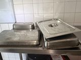 two trays of food sitting on a stainless steel counter