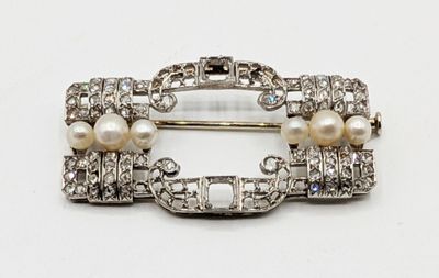 une image représentant une broche ornée de perles et de diamants sur fond blanc