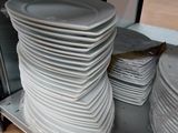 beaucoup d'assiettes empilées sur une étagère dans la cuisine