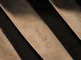 several knives are lined up on a black surface with a yellow handle