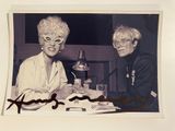 photo dédicacée représentant deux femmes assises à une table devant une lampe