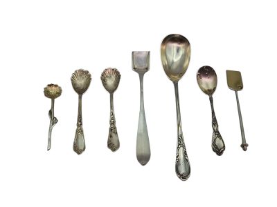 six spoons and a spatula are lined up on a white surface