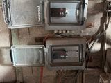 trois compteurs électriques fixés au mur d'un immeuble, auxquels sont raccordés des fils
