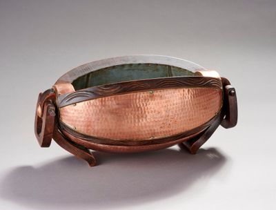 copper bowl with handle and handles on a white surface