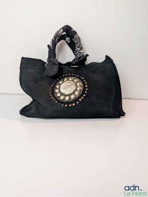 a black purse with a phone on it on a table