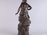 an antique bronze statue of a woman on a rock with a bird on her shoulder