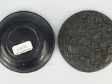 two black plates with a white label on them sitting on a white surface