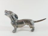 a small silver dog statue on a white surface
