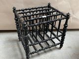 une petite cage en métal sur laquelle sont enfilées plusieurs perles noires