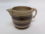 a brown and black striped pitcher on a white table