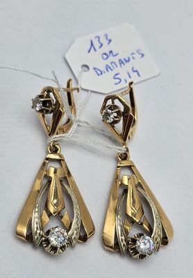 une paire de boucles d'oreilles dorées ornées de diamants sur fond blanc
