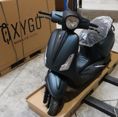 un scooter posé sur une palette devant une boîte