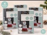 trois boîtes de « kniscuits » posées sur une table à côté d'un sapin de Noël