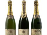 trois bouteilles de champagne posées les unes à côté des autres sur une surface blanche