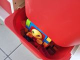 un bac rouge posé par terre, contenant des jouets